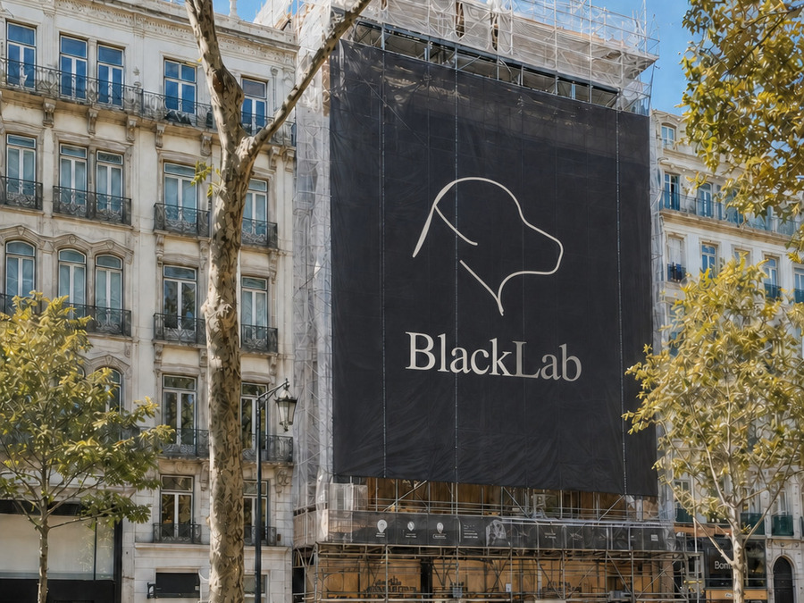 A building under renovation on a Lisbon avenue, its scaffolding wrapped in a dark hoarding carrying the BlackLab mark.