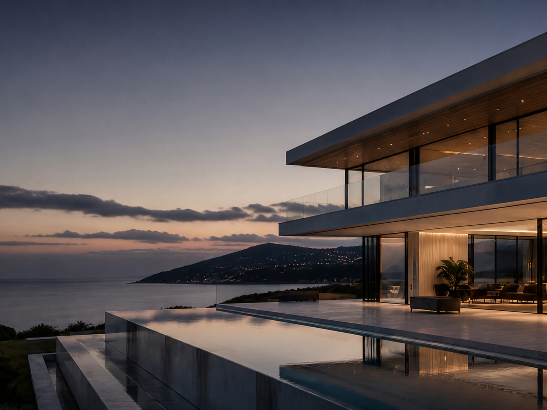 A contemporary clifftop house at dusk, its glazed upper floor cantilevered above an infinity pool and the sea.